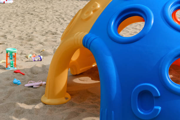 toy house and plastic digger etc on sand in a sunny day