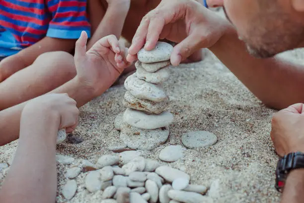 Photo of Child's hand  building stone pyramid  with dad