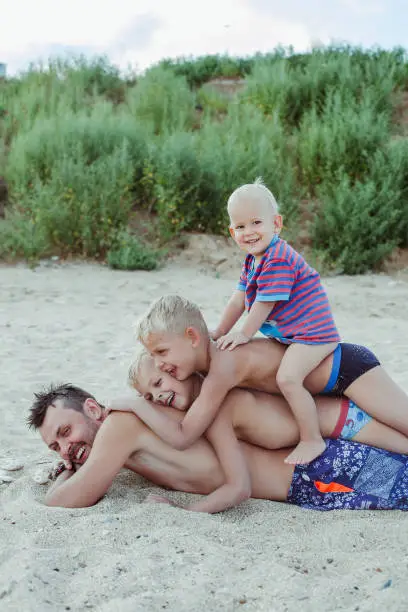 Photo of Dad and sons are having fun on the beach in summer