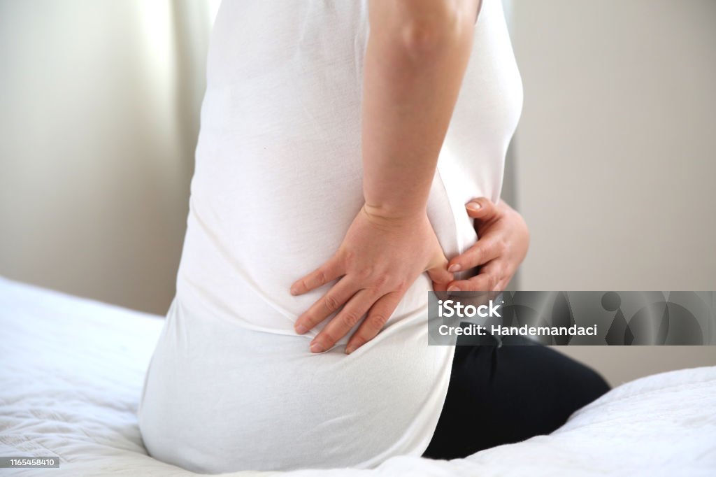 Closeup of young woman suffering from pain kidney disease while sitting on bed at home, Healthcare And Medicine concept stock photo Organ, Acute Angle, Dialysis, Pregnant Kidney - Organ Stock Photo
