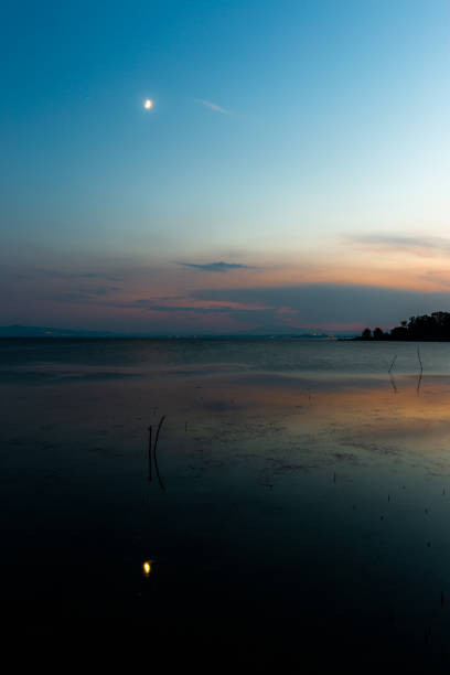 istock Moon above a lake with its reflection on the Trasimeno lake surface at dusk 1165458671