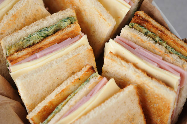 istock White bread sandwiches occupy the entire frame space. Square-shaped sandwiches stuffed with ham, cheese and scrambled eggs with spinach. 1165460408