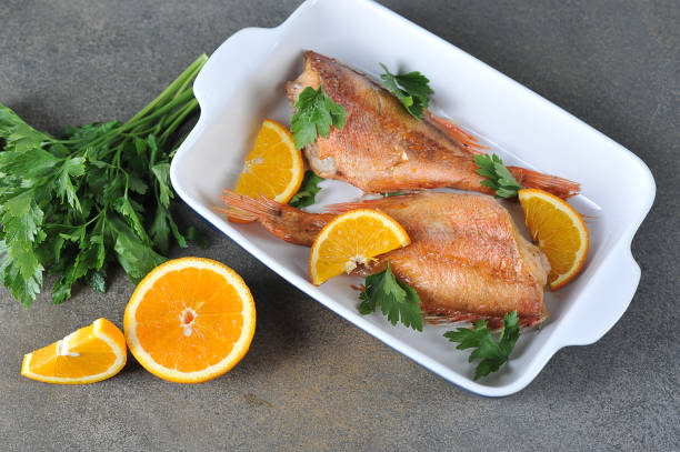Baked Sebastes with oranges. View from above. Close-up. Baked Sebastes with oranges. Gray background. View from above. Close-up. snapper head stock pictures, royalty-free photos & images