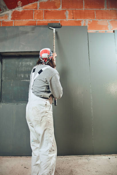 istock Painter painting walls with a extender roller indoors. 1165462936