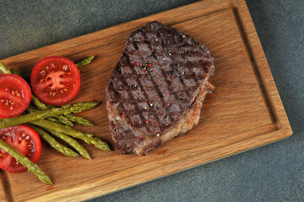 steak with asparagus and tomatoes on a wooden board. steak cooked on the grill. view from above. - scotch steak imagens e fotografias de stock