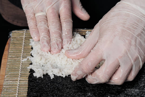 istock Cook's hands close-up. The chef makes sushi and rolls from rice. White gloves. 1165463869