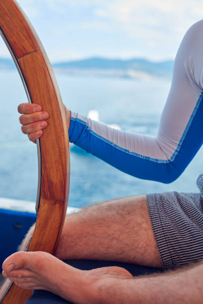 istock Sailor using wheel to steer rudder on a sailing boat. 1165463895
