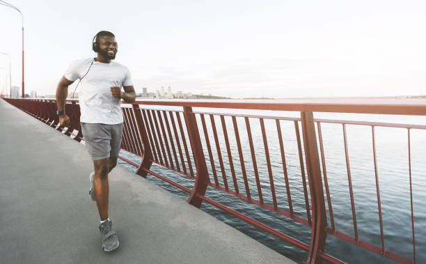 istock Young afro guy is enjoying running by the bridge 1165465300