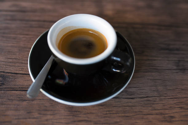 Cup of hot espresso coffee and coffee crop on wood board