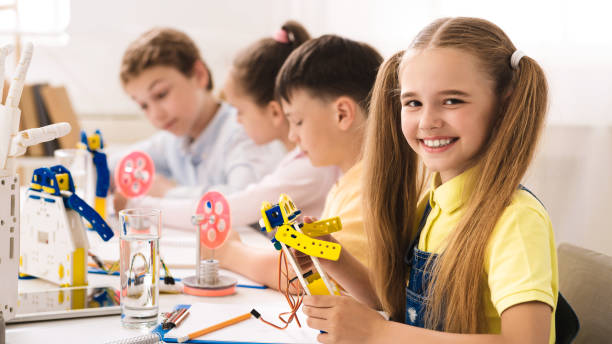 istock Friendly schoolgirl holding robot model in classroom 1165465636