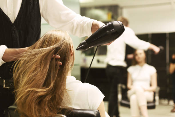 estilista secado de pelo de niña con secador de pelo en el salón de belleza - salón de belleza fotografías e imágenes de stock