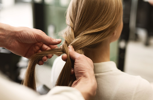 Professional Stylist Braiding Girl's Long Hair In Beauty Salon. Selective Focus, Closeup. Panorama With Empty Space For Text