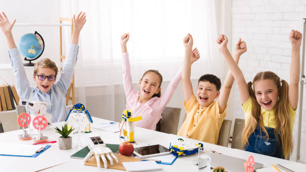 istock Happy children with raised hands after robotics class 1165466860
