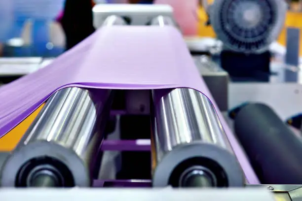 Close-up of purple cloth at textile equipment's conveyor belt.