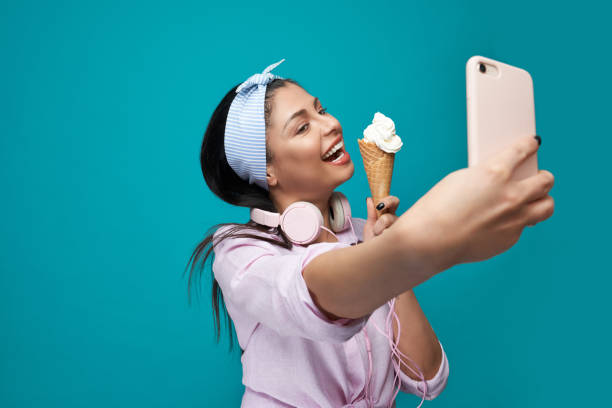 Smiling model taking selfie, holding ice cream.