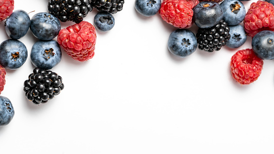 Top view and close up of mix ripe, yummy and sweet blueberries, blackberries, raspberries fruits on white background with copy space