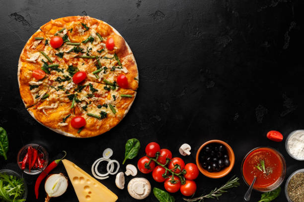 istock Delicious pizza with tomatoes and herbs on black table 1165471405