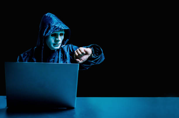anonymer computer-hacker in weißer maske und hoodie. verschleiertes dunkles gesicht mit laptop-computer für cyber-angriff und überprüfung der zeit, datendieb, internet-angriff, darknet und cyber-sicherheitskonzept. - zeitdieb fotos stock-fotos und bilder