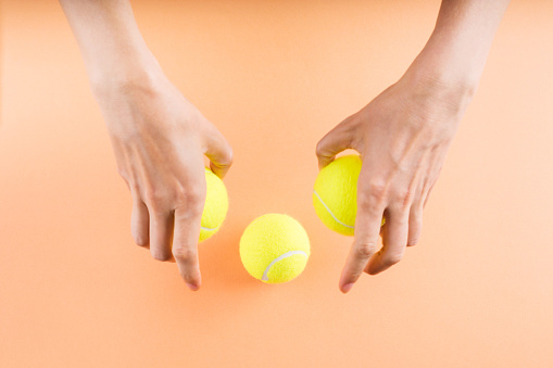 Three tennis balls on orange in woman's hands