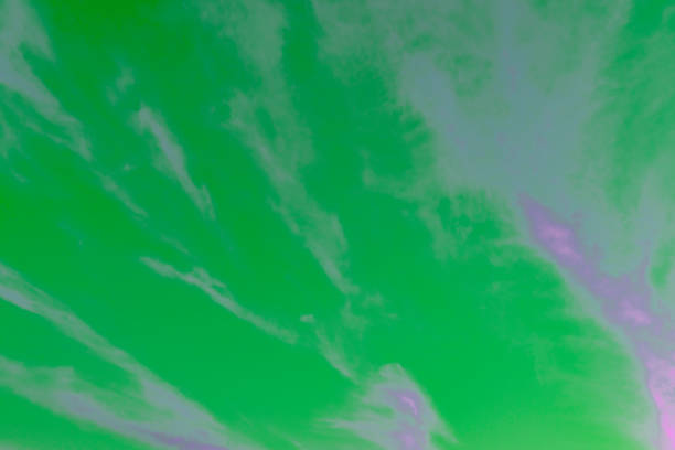 Pink cirrus clouds in a setting sky over France, ideal as a background. It has been colourshifted to create a green sky and purple clouds.
