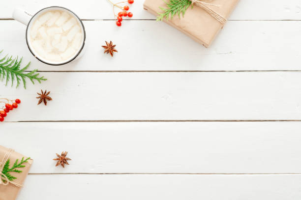 istock Christmas composition. Flat lay cup of hot chocolate with marshmallow, fir tree branches, red berry, presents on wooden white table. Christmas, winter holiday, New year concept. Postcard template. 1165475792