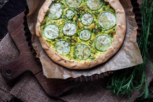 istock Homemade courgette and goat cheese pie on a dark rustic wooden board background 1165477712