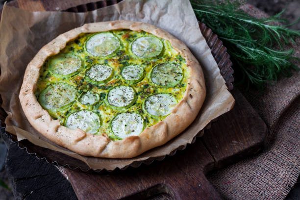 istock Homemade courgette and goat cheese pie on a dark rustic wooden board background 1165477892