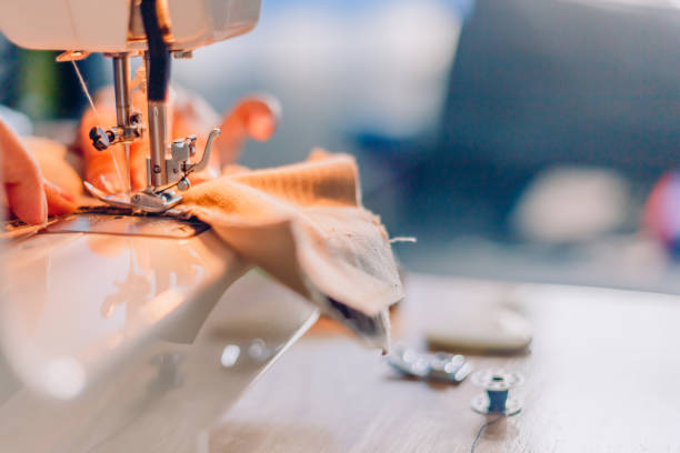 istock Close up hands of sewing process. Female hands stitching fabric on  machine hobby at home. blurred background. 1165478069