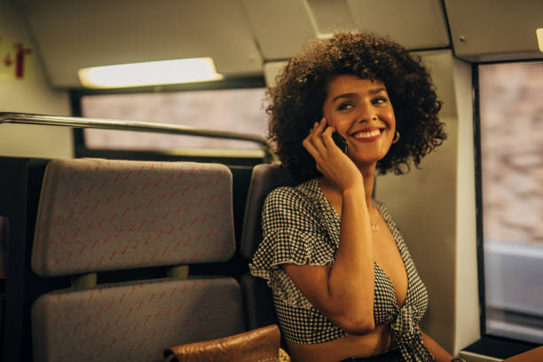 istock Curly haired woman talking on mobile in train 1165480200