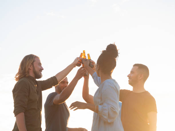 istock Smiling friends clinking beer bottles during picnic. 1165480531