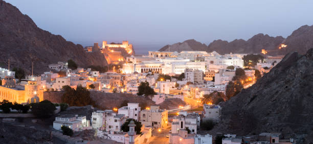 edifícios velhos de muscat após o por do sol com uma vista sobre o forte do al jalai, médio oriente, oman. - islam mosque oman greater masqat - fotografias e filmes do acervo