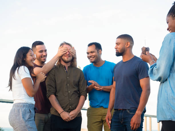 istock Front view of smiling friends making surprise for young man. 1165486633