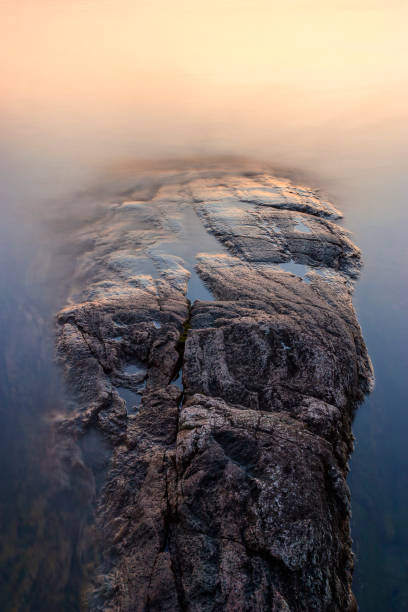 Abstract cliff at the water's edge with smooth water in sunset light