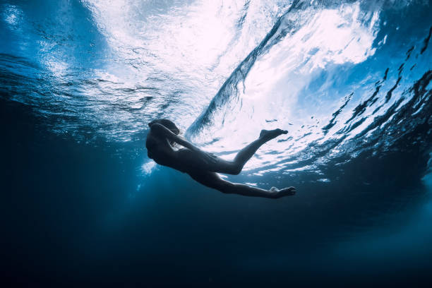 istock Young woman dive underwater with under barrel wave 1165493232