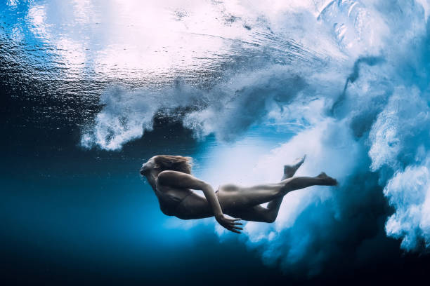 istock Woman swim underwater with big ocean wave. 1165493234