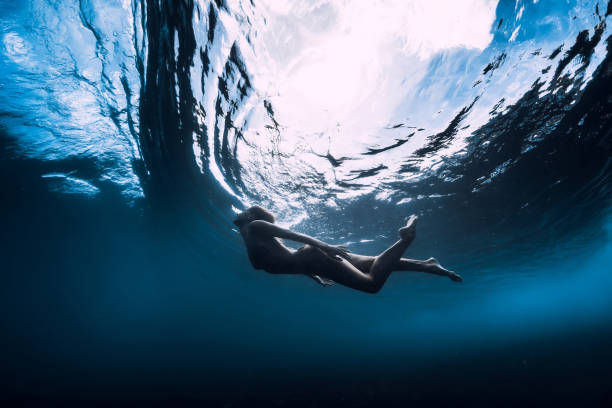 istock Slim woman dive underwater with under barrel wave 1165493261