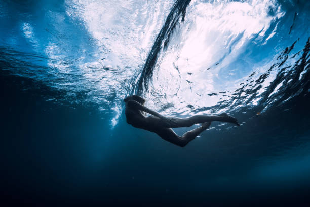 istock Young woman dive underwater with under barrel wave 1165493316