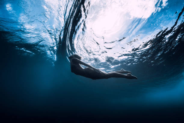 istock Slim woman dive underwater with under barrel wave 1165493349