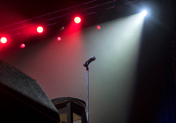 istock Microphone on stage with stage-lights in the background. 1165498260