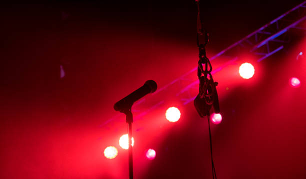 istock Microphone on stage with stage-lights in the background. 1165498275