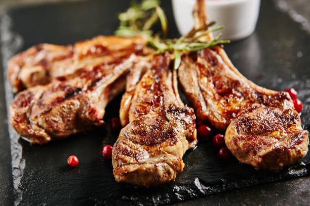 Grilled Lamb Chops Grilled Lamb Chops with Cranberries and Rosemary on Natural Black Stone Background. Roasted Cutlets on Creative Restaurant Backdrop. Mutton Ribs with Spices and Sause halal stock pictures, royalty-free photos & images