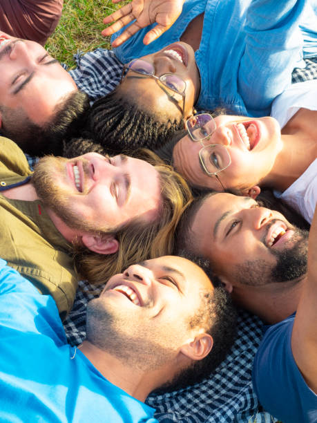 istock Happy friends lying and laughing in park 1165502761