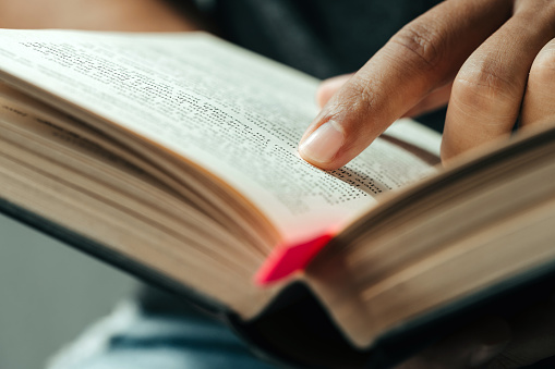 close-up of finger pointing text in Bible.close up of man reading through the Bible.