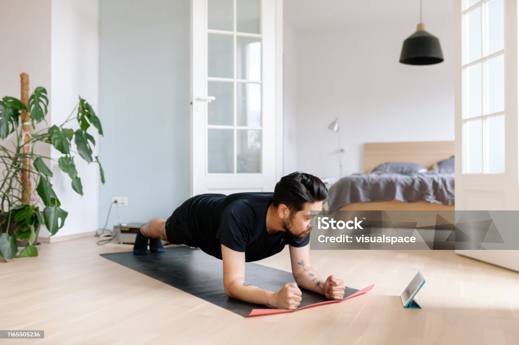 Asian man uses digital tablet to lean plank position Photo series of a japanese man working out at home, watching youtube videos and learning the exercises. Exercising Stock Photo