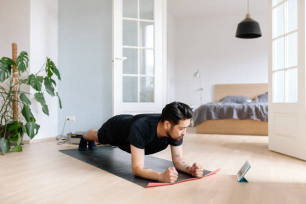 o homem asiático usa a tabuleta digital para inclinar a posição da prancha - men exercising equipment relaxation exercise - fotografias e filmes do acervo
