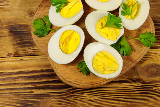 istock Boiled eggs with parsley on cutting board on a wooden table. Top view 1165505427