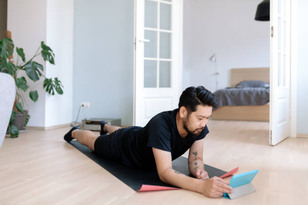 istock Asian man uses digital tablet while working out at home 1165506985