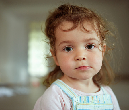 Happy young caucasian preschooler boy in casual outfit smiling, looking to the side, isolated over pastel blue background.