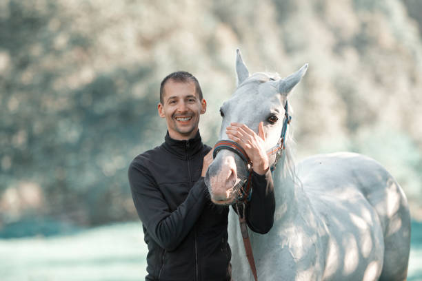 istock Man smiling next to a white horse 1165509966