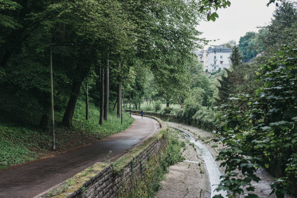 Path by the Petrusse stream inside a park in Luxembourg City. Luxembourg City, Luxembourg - May 19, 2019: Path by the Petrusse stream inside a park in Luxembourg City. One third of the surface of the city is shaped by beautifully landscaped green spaces. petrusse stock pictures, royalty-free photos & images